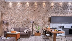Een moderne woonkamer met een stenen muur, een bank, een salontafel, en een eethoek met stoelen en een houten tafel.