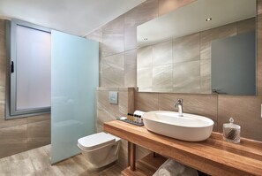 Une salle de bain moderne avec un grand miroir, un meuble-lavabo en bois, un lavabo blanc et une cabine de douche en verre.