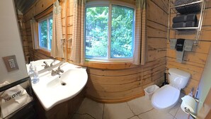A bathroom with wooden walls, a sink, a toilet, and a window with curtains. - Log Cabin in North Georgia Mountains (Dahlonega)