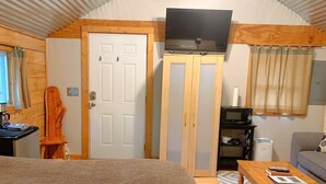 A bedroom with a bed, a TV, a wooden wardrobe, a desk with a computer, and a window with curtains. - Log Cabin in North Georgia Mountains (Dahlonega)