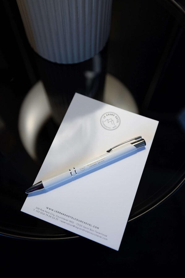 A brochure with a pen and hotel information on a black chair. - Le Grand Hotel Courchevel 1850 (Courchevel)