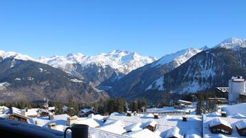 Un village de montagne aux bâtiments recouverts de neige, offrant une vue dégagée sur des montagnes aux sommets enneigés.
