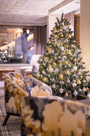 A Christmas tree with ornaments, a patterned armchair, and a staircase in the background.