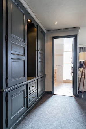 A hallway with dark wooden cabinets, a carpeted floor, and a doorway leading to a bathroom. - Le Grand Hotel Courchevel 1850 (Courchevel)