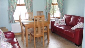 Une pièce comprenant un canapé en cuir rouge, une table à manger en bois avec des chaises, et un divan en cuir rouge.