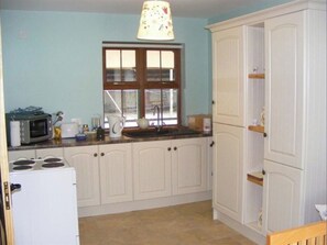 Compact kitchen with a refrigerator, microwave, stove, and countertop with kitchen essentials.