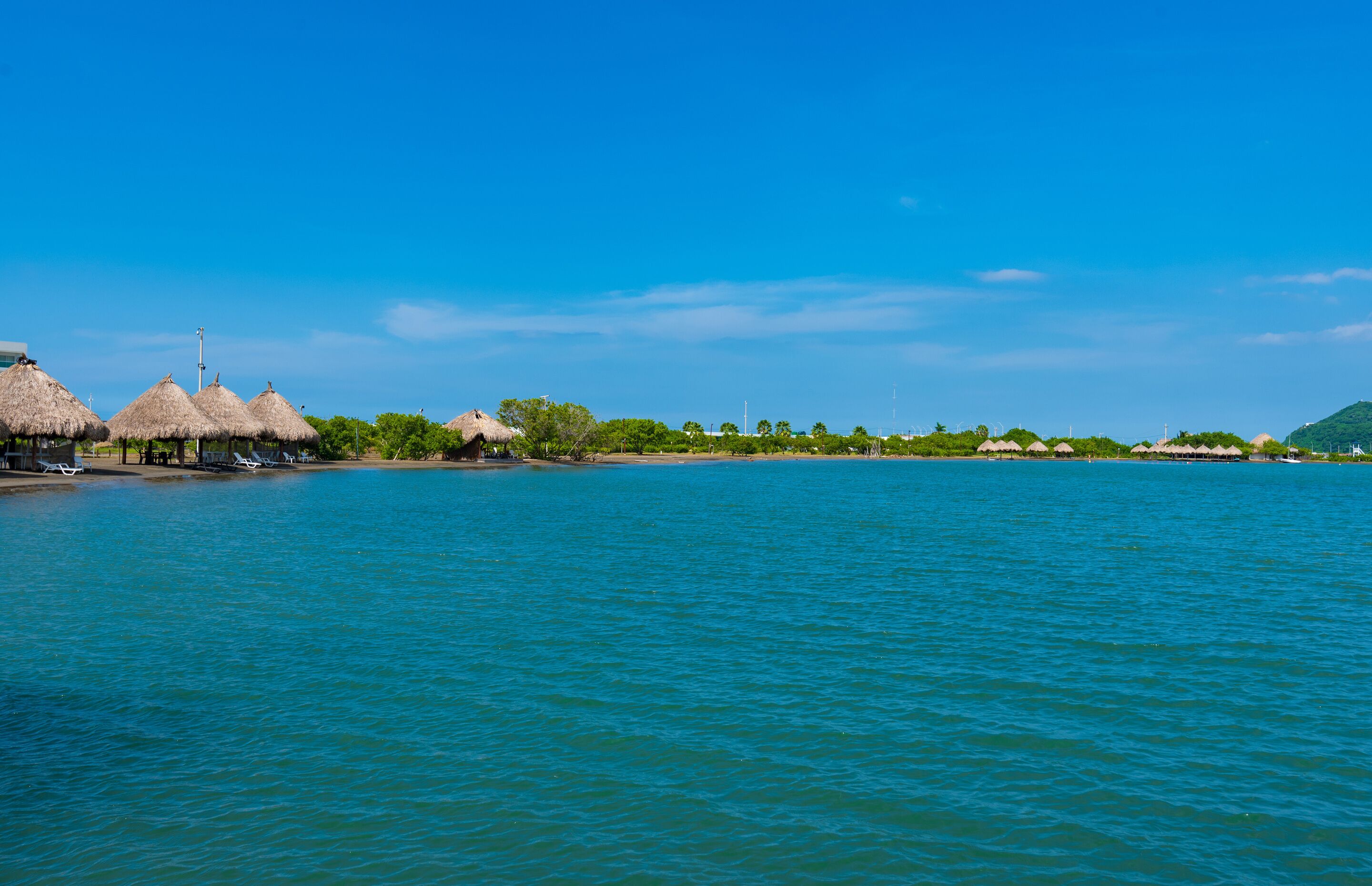 A coastal area with thatched-roof huts and a calm sea.