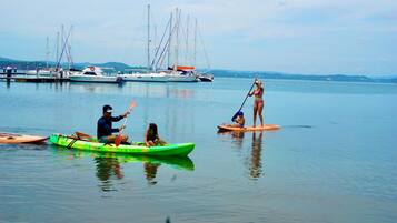Un puerto tranquilo con varias embarcaciones, incluyendo un kayak verde y una tabla de remo.