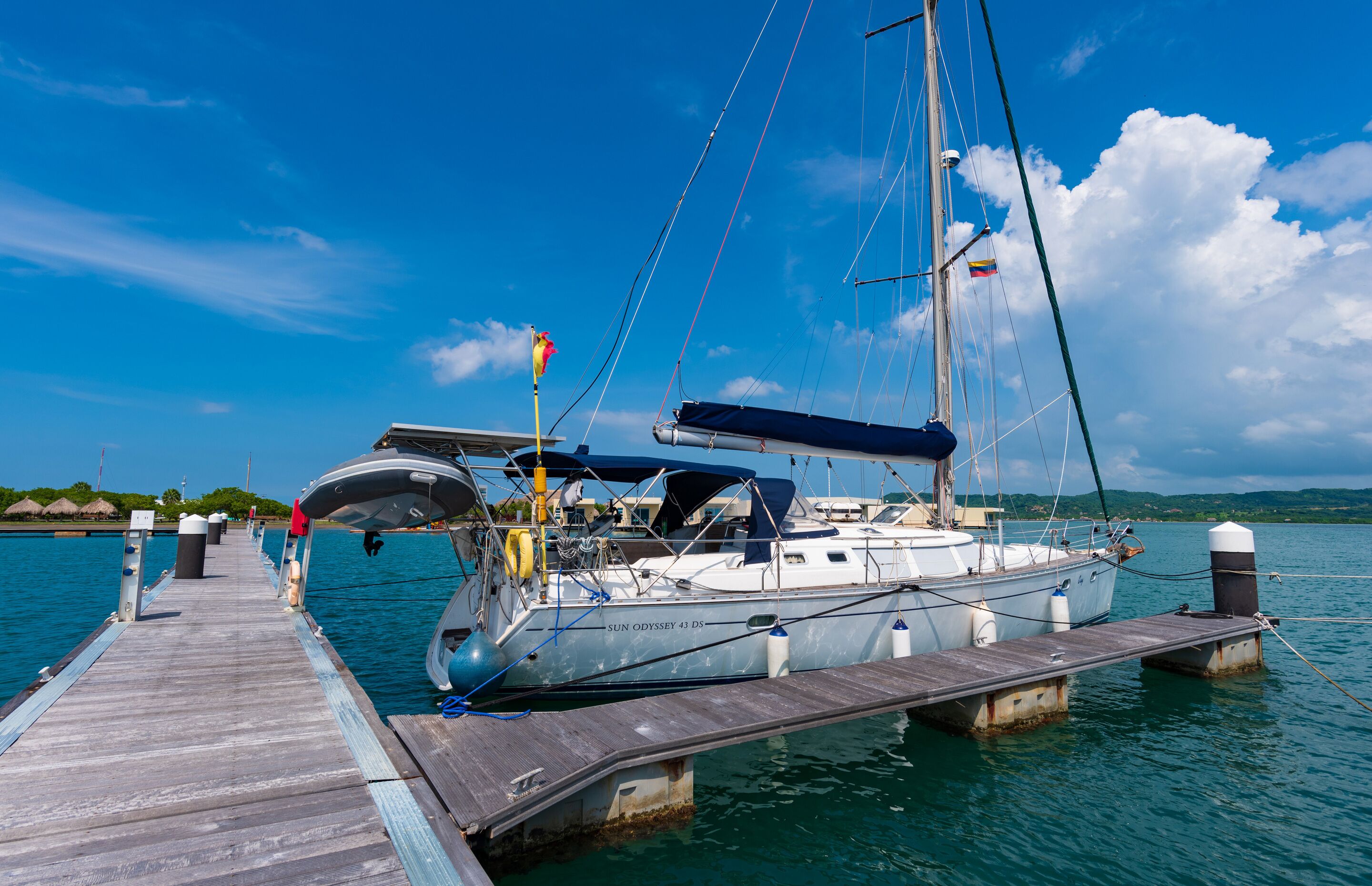 A sailboat docked at a wooden pier with a clear blue sky and calm water.
