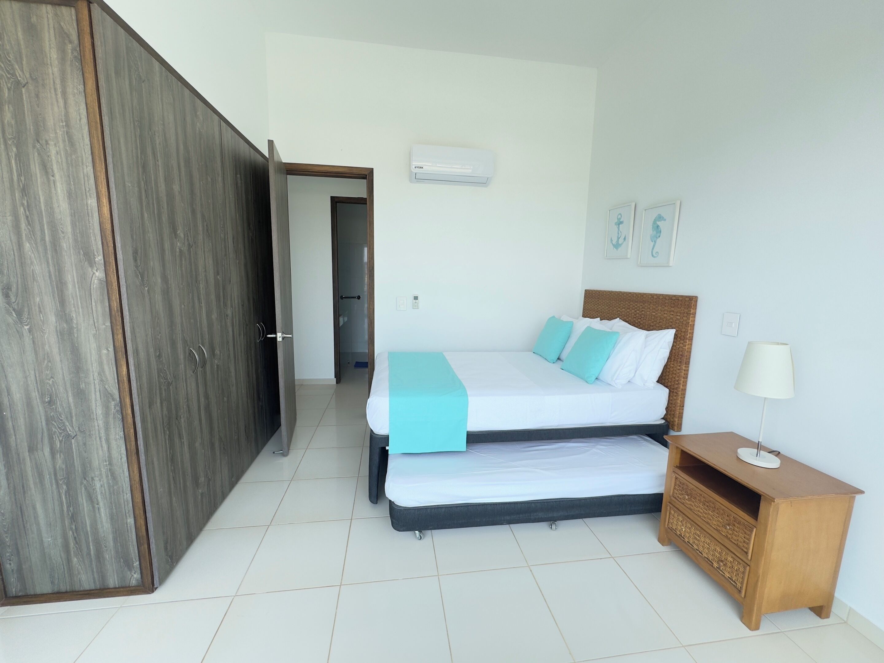 A bedroom with a bed, a nightstand, a wardrobe, and an air conditioning unit.