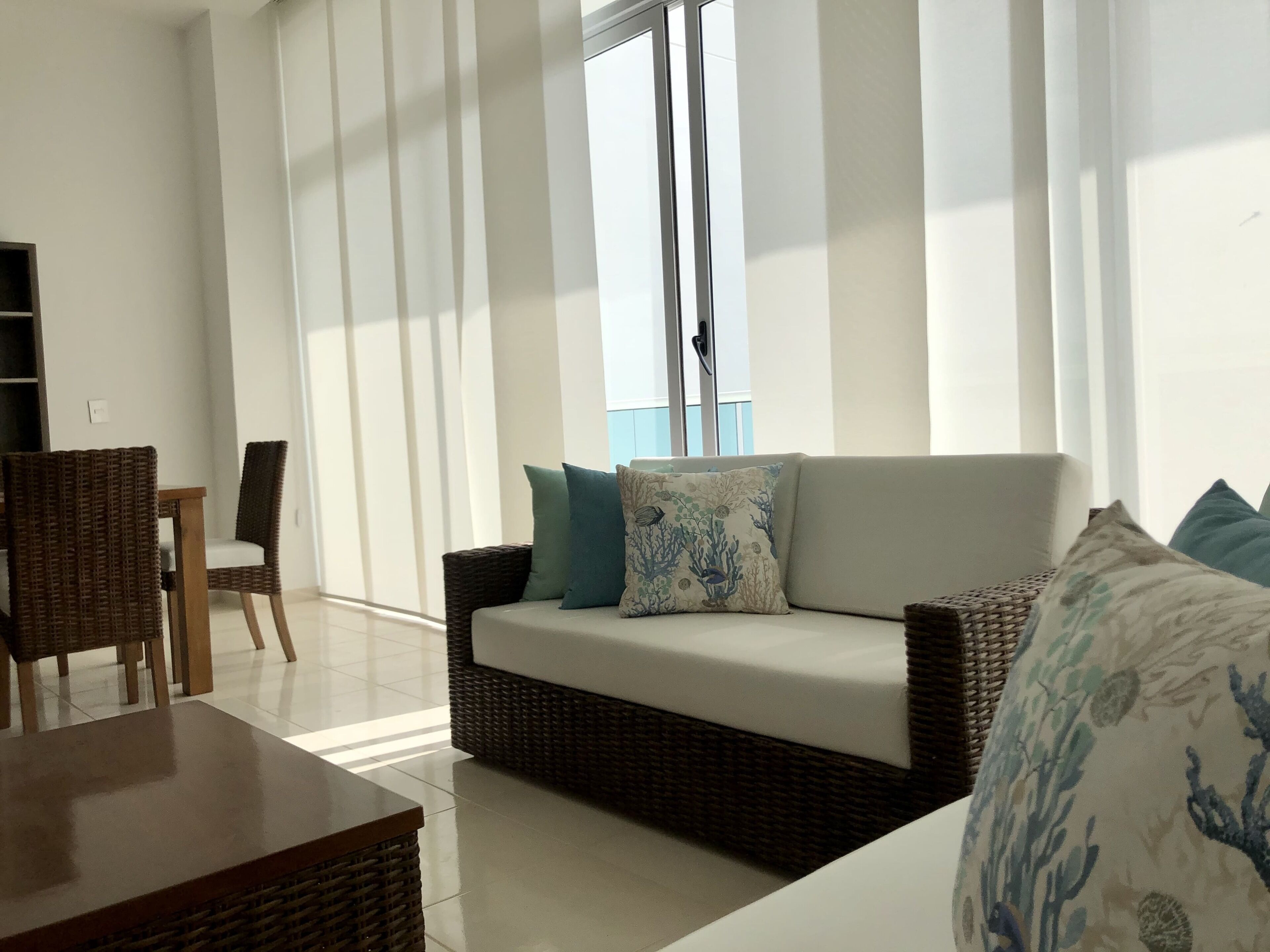 A living room with a wicker sofa, a wooden table, and a chair.