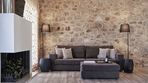 En moderne stue med en stenvæg, en sofa, en skammel og to gulvlamper.