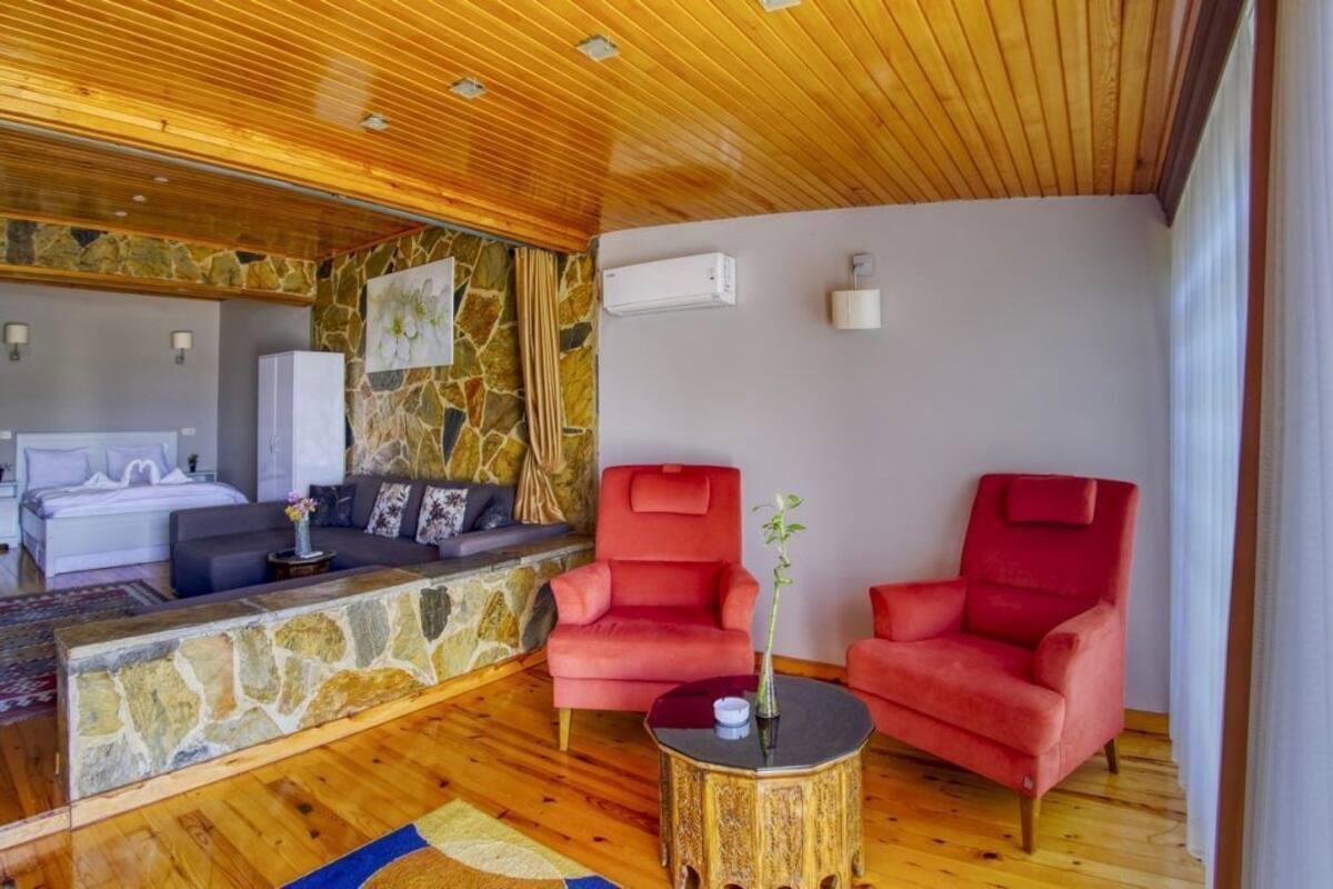 A cozy room with a stone accent wall, a bed, a red armchair, and a small table with a vase.
