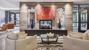 A modern living room with a fireplace, two sofas, a coffee table, and a large abstract painting above the fireplace. - The Lion E206 (Vail)