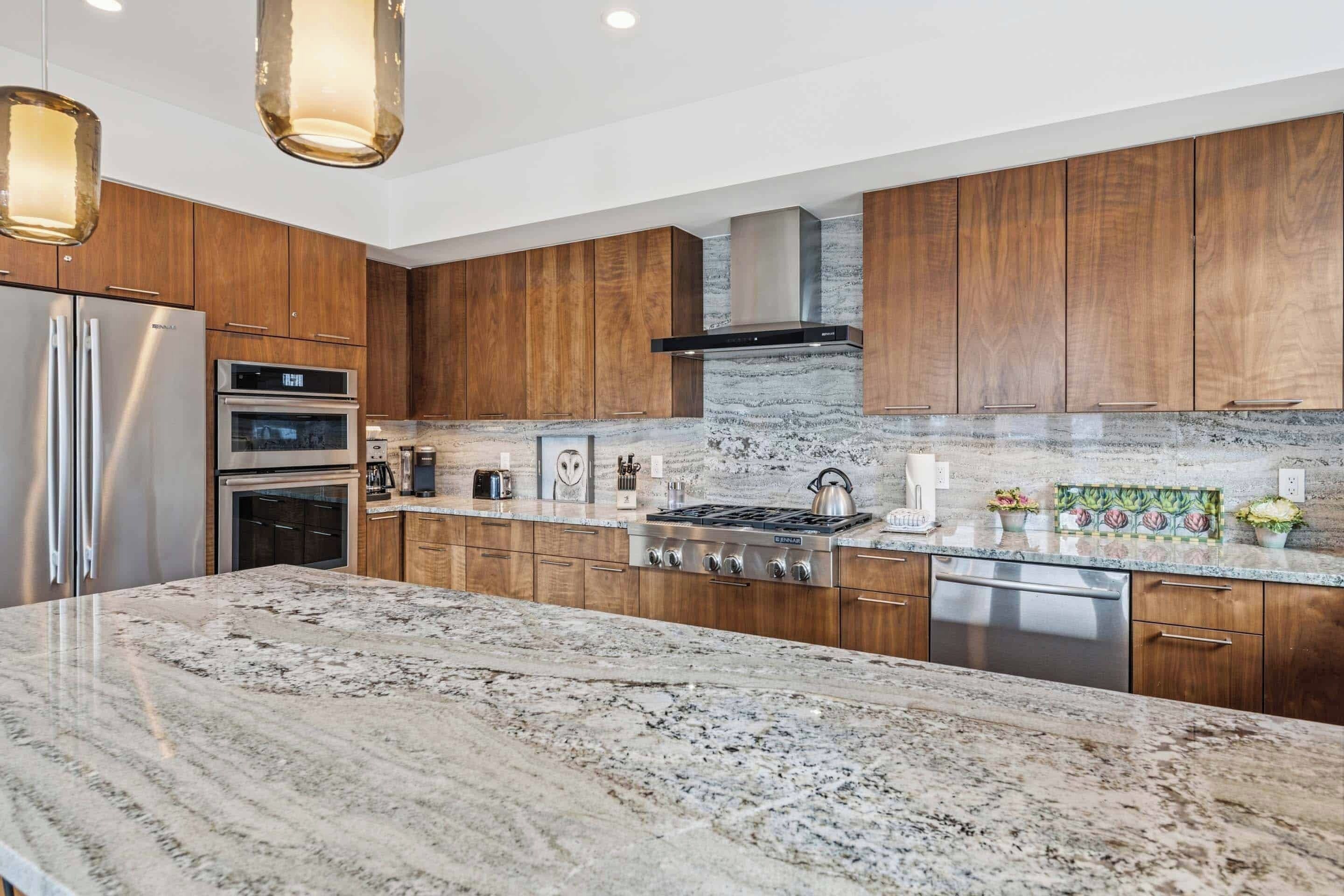 A modern kitchen with wooden cabinets, stainless steel appliances, and a granite countertop.