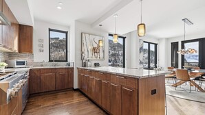 A modern kitchen with wooden cabinets, a marble countertop, and pendant lighting. - The Lion Residences W602 (Vail)