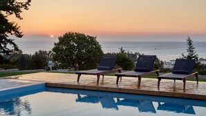 A poolside area with lounge chairs and a view of the sunset over the ocean. - Iconic SeaView Villa, with Private Pool & 3Bedrooms (Rodos)