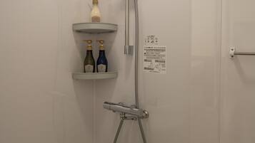 Un bagno con doccia, servizi igienici e due ripiani con bottiglie.