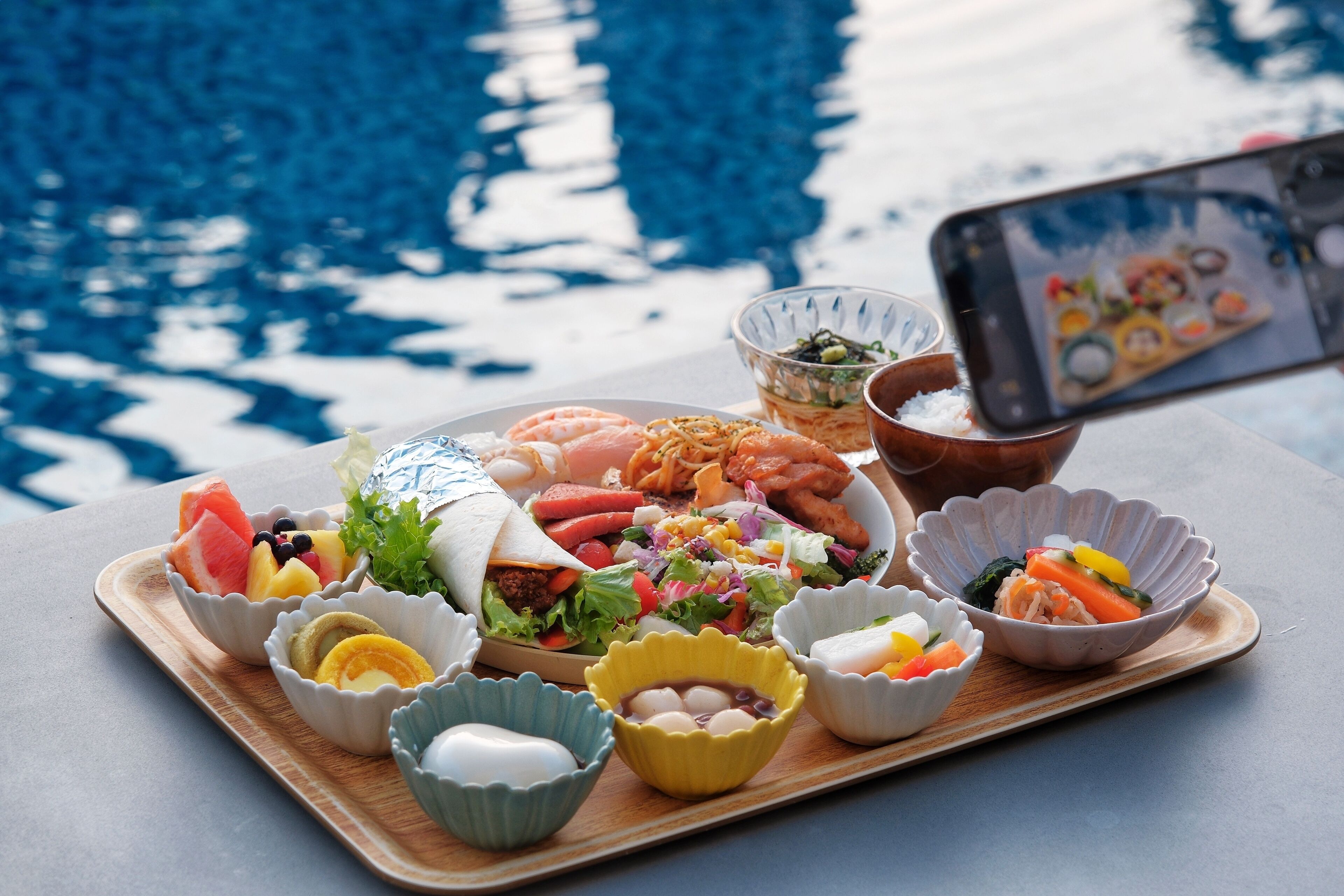 Diversos alimentos en una bandeja junto a una piscina.