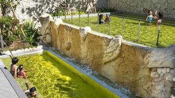 Une piscine avec un mur en pierre et une zone herbeuse.