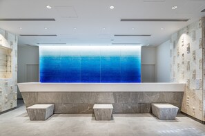 A modern bathroom with a large glass wall, marble flooring, and a reception desk. - Okinawa Hinode Resort and Hot spring Hotel (Naha)