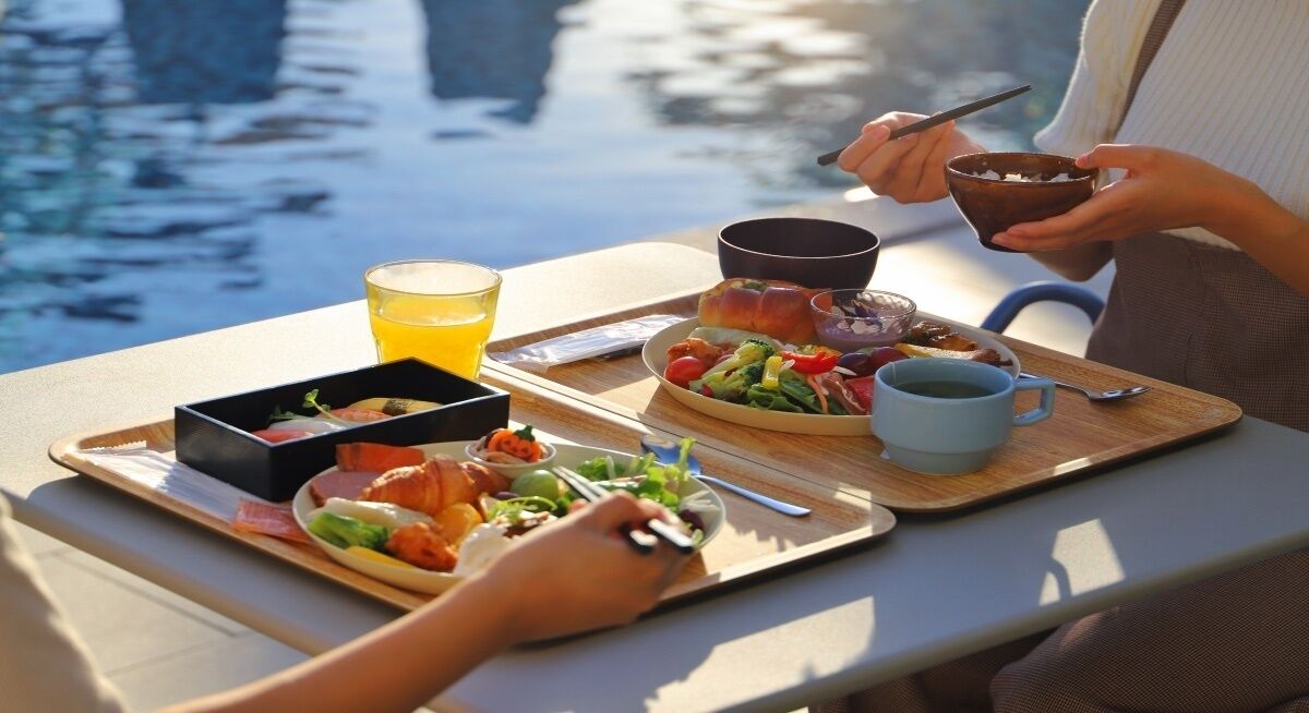 Una bandeja con comida y bebidas sobre una mesa junto al agua.