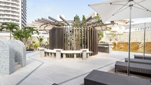A modern outdoor lounge area with seating and a central decorative structure.