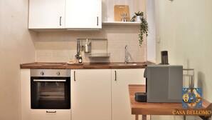A modern kitchen with white cabinets, a built-in oven, a coffee machine, and a wooden countertop.