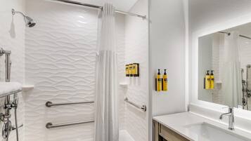 Un baño moderno con cabina de ducha de vidrio, un lavamanos blanco y un espejo grande.