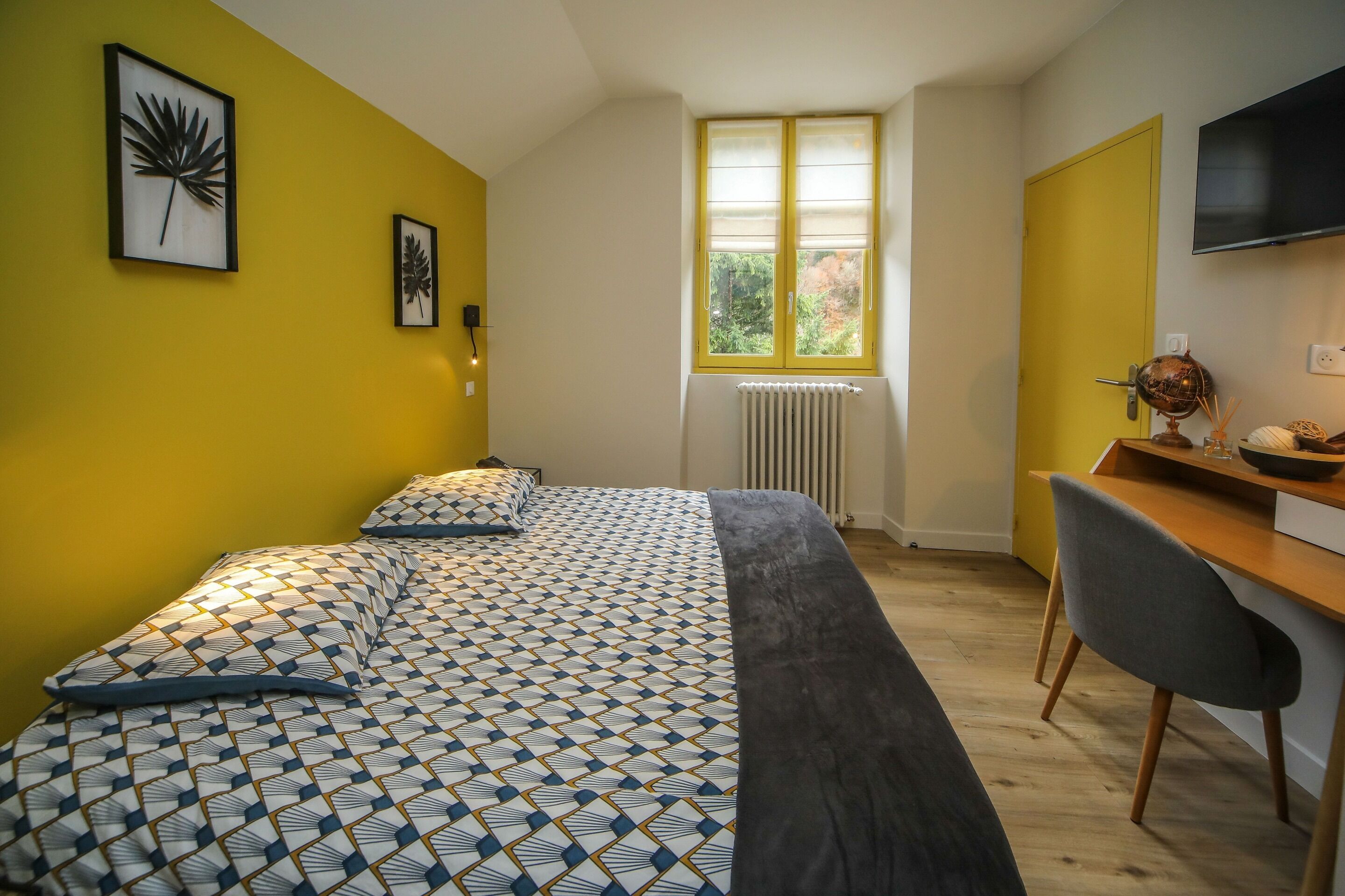 Un dormitorio con cama, escritorio y silla. Hay una ventana con persianas y un radiador.