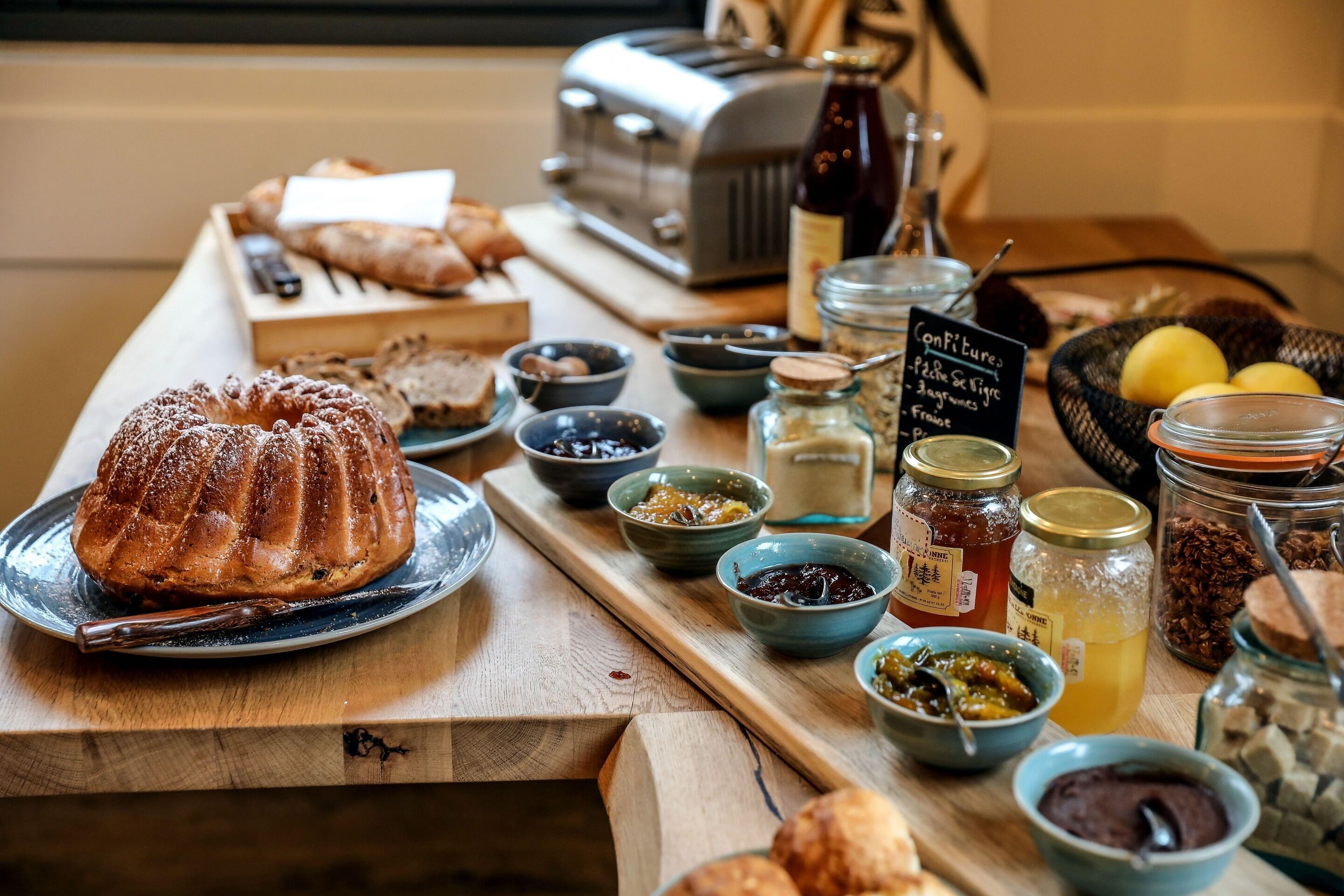 A breakfast buffet with various breads, jams, and spreads.