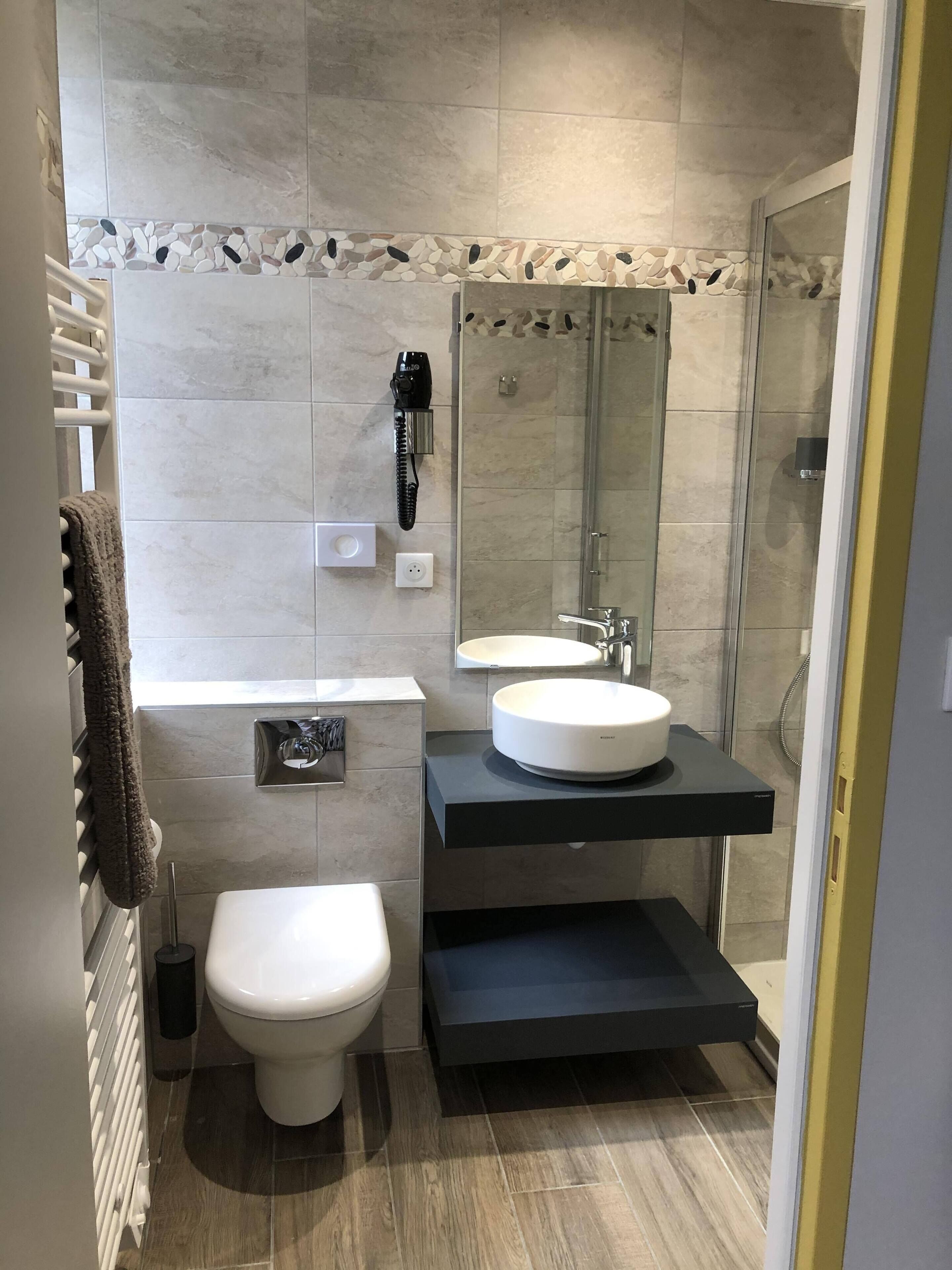 A modern bathroom with a white toilet, a sink, and a glass-enclosed shower.