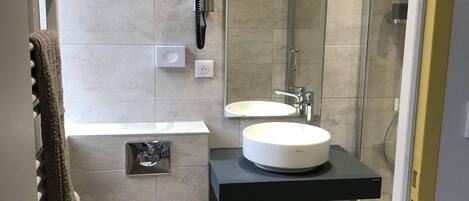 A modern bathroom with a white toilet, a sink, and a glass-enclosed shower.