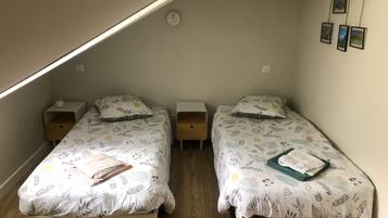 Une petite chambre agréable, dotée de deux lits simples, chacun avec une table de chevet. La chambre a un plafond en pente et une petite fenêtre.