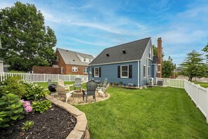 Un jardin à l’arrière d’une maison, avec une pelouse, un barbecue et des meubles d’extérieur.