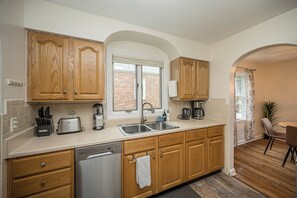A kitchen with wooden cabinets, a stainless steel sink, a toaster, and a coffee maker.