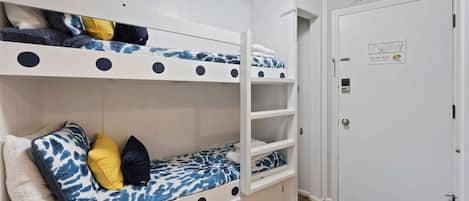 Une chambre avec des lits superposés, une porte portant l’inscription « Maison d’hôtes » et une carte accrochée au mur.