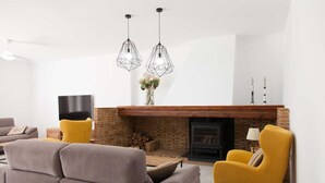 A modern living room with a fireplace, two yellow chairs, a grey sofa, and a TV. - Villa with Private Pool (Alberique)