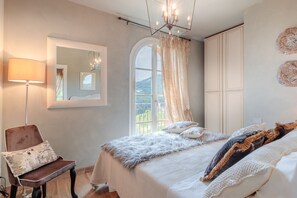 A bedroom with a large bed, a chair, a mirror, and a wardrobe.