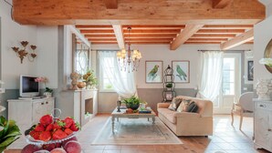 A spacious living room with a high ceiling, wooden beams, a fireplace, a sofa, a coffee table, and a television. - VILLA REGINA, 4 bedrooms and a luxury style among the vineyards by Lucca Town (Lucca)