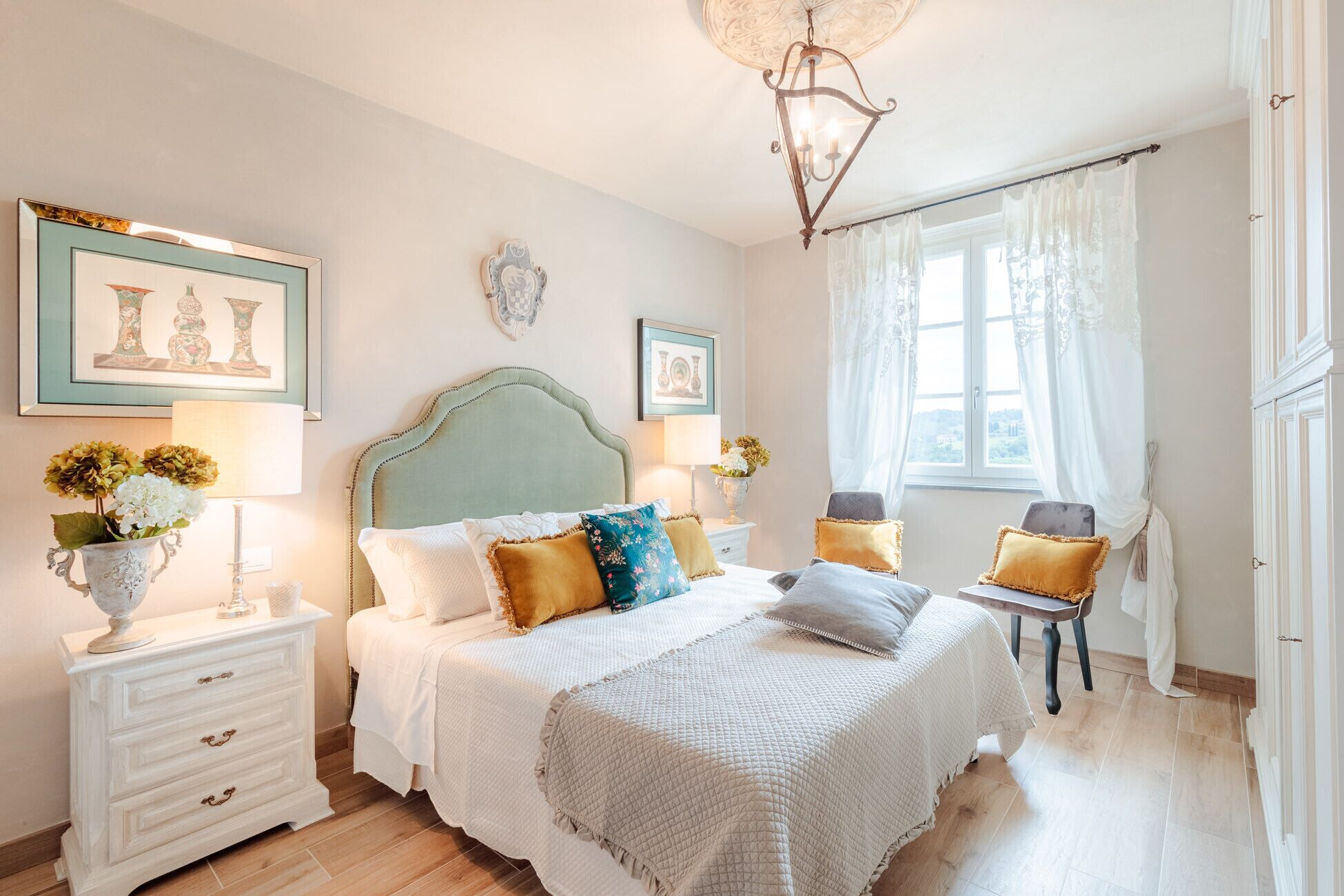A bedroom with a bed, bedside tables, a chair, and a window with curtains.