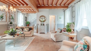 A spacious living room with a high wooden ceiling, a chandelier, and a large window with curtains. - VILLA REGINA, 4 bedrooms and a luxury style among the vineyards by Lucca Town (Lucca)