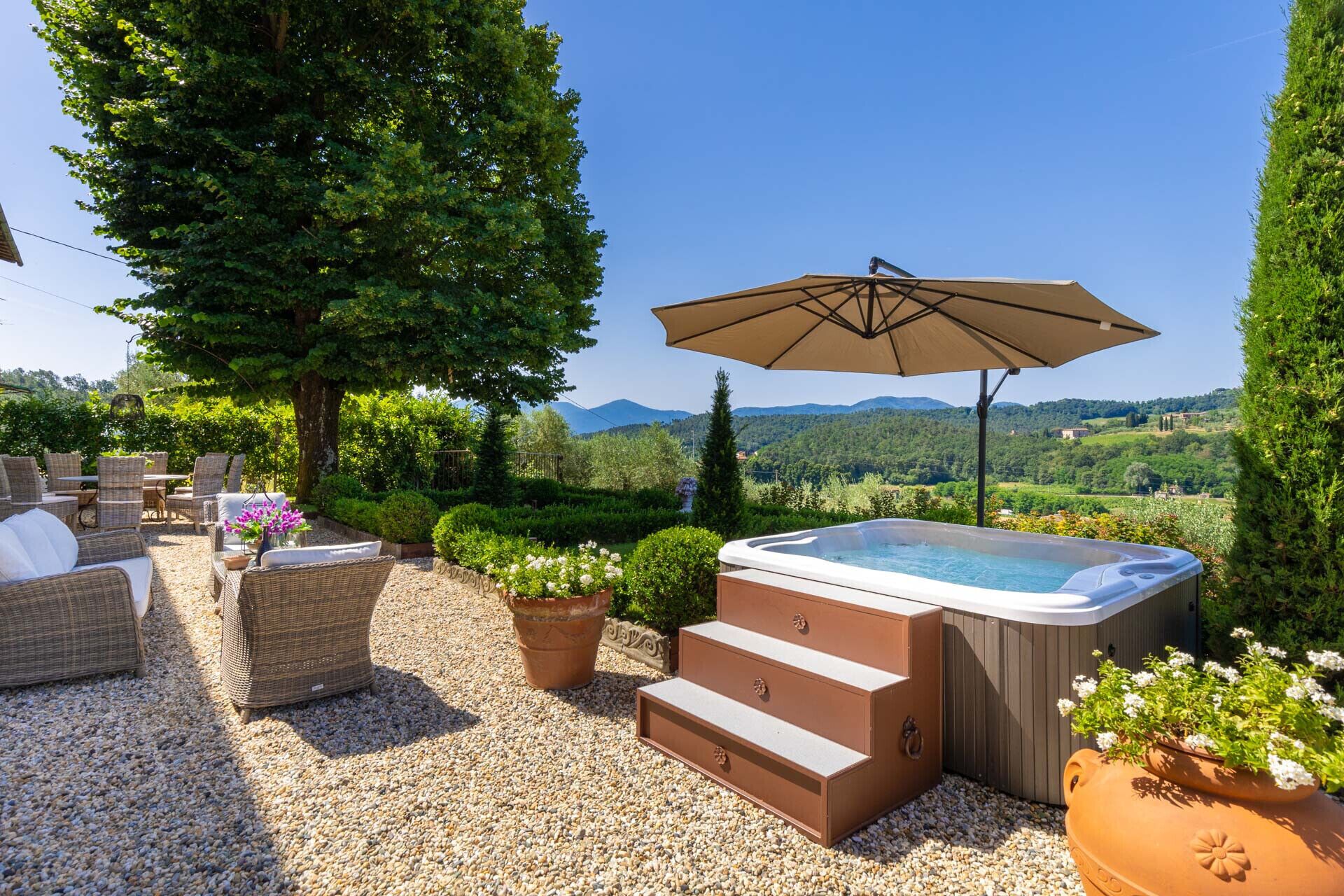 An outdoor patio with wicker furniture, a hot tub, and a view of the countryside.