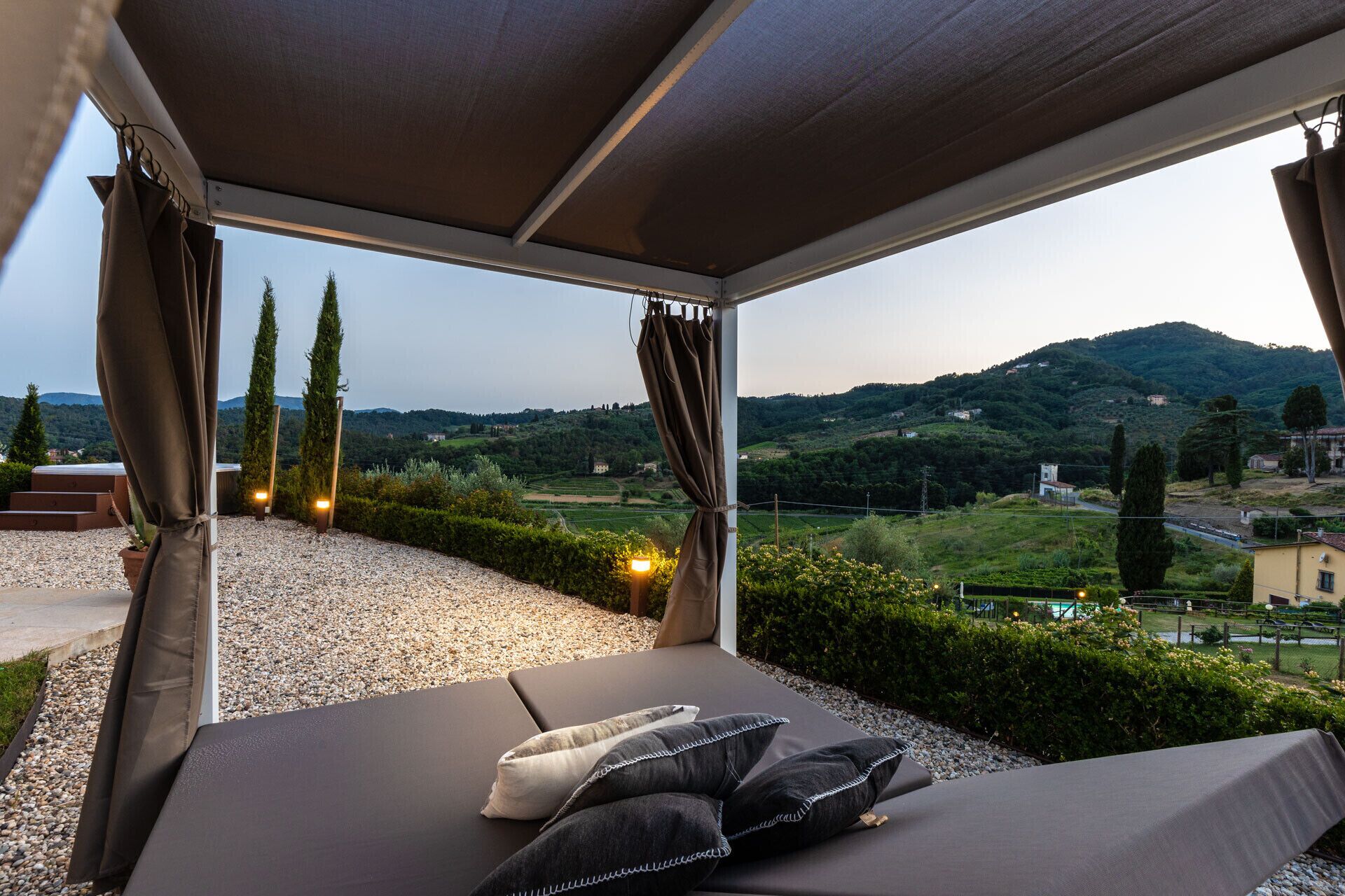 A covered outdoor seating area with a view of a hillside landscape.