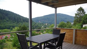 Ein Balkon mit Tisch und Stühlen mit Blick auf ein bewaldetes Tal.