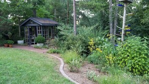 Un jardín con un gazebo de madera, rodeado de diversas plantas y árboles.