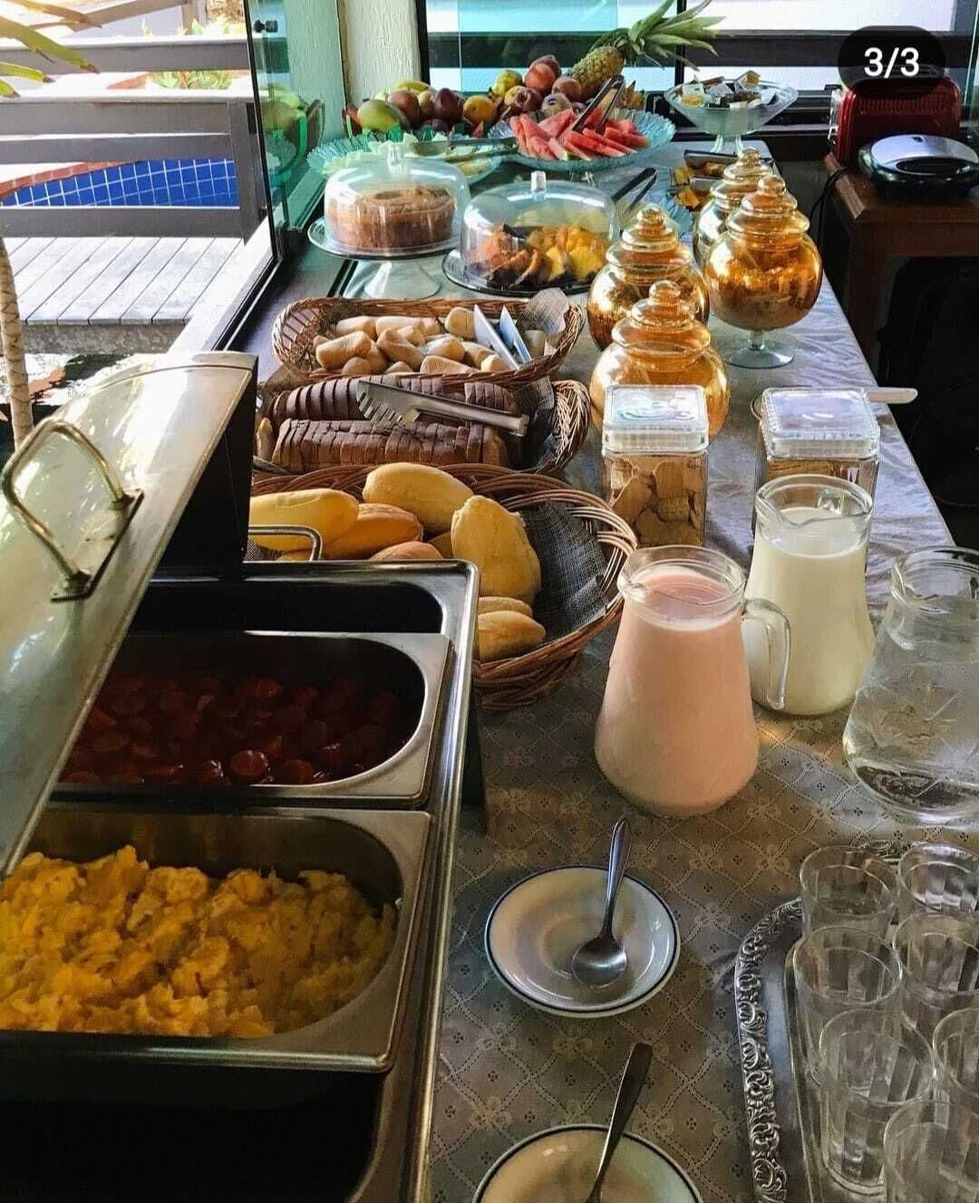 A buffet with various food items and beverages, including fruits, pastries, and milk.