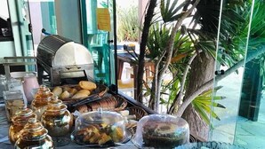 Une table de buffet proposant une variété d’aliments, notamment des fruits, des légumes et des pâtisseries.