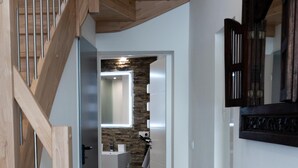 A hallway with a wooden staircase, a stone wall, and a modern bathroom with a mirror and sink. - Vacation with a view of the unique Marksburg Castle (Braubach)