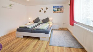 Ett sovrum med en säng, sängbord, ett fönster med gardiner, ett element och en vägg med dekorativa detaljer.